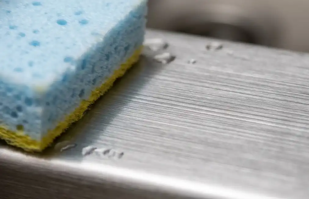 Close-up of stainless steel grain lines showing the correct scrubbing direction along the brush finish to prevent scratches.