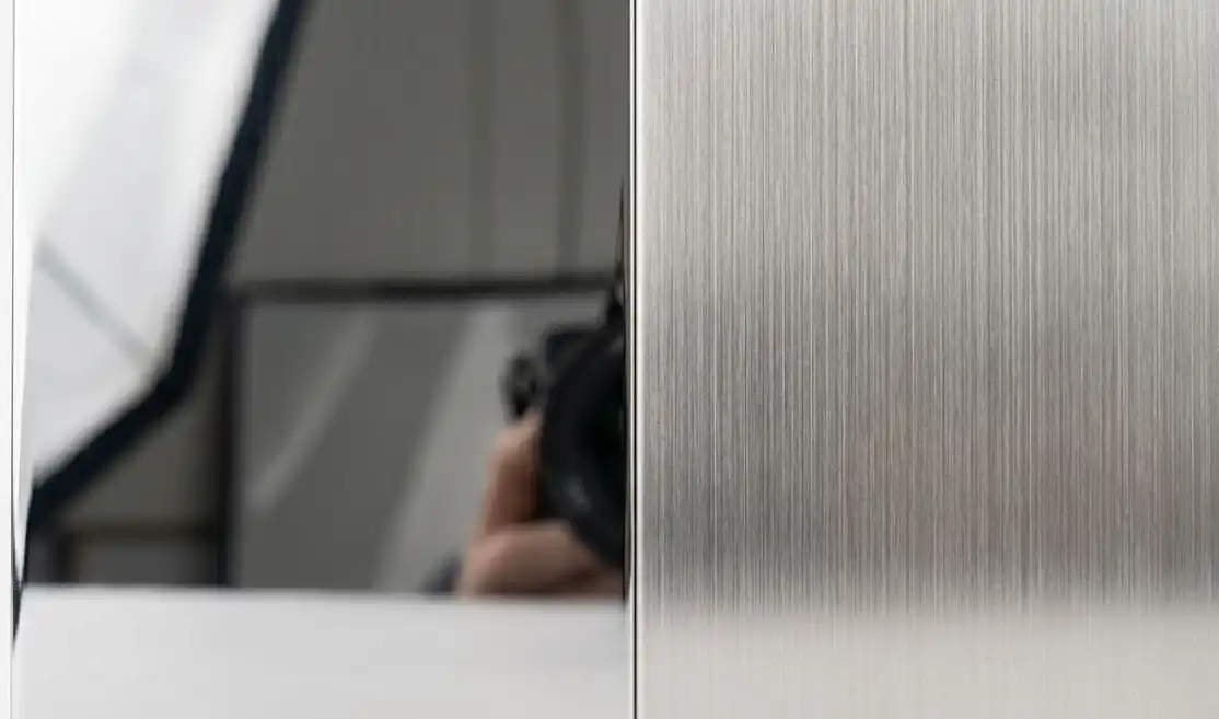 Macro comparison showing the difference in light reflection between a shiny mirror-polished stainless steel surface and a soft brushed satin finish.